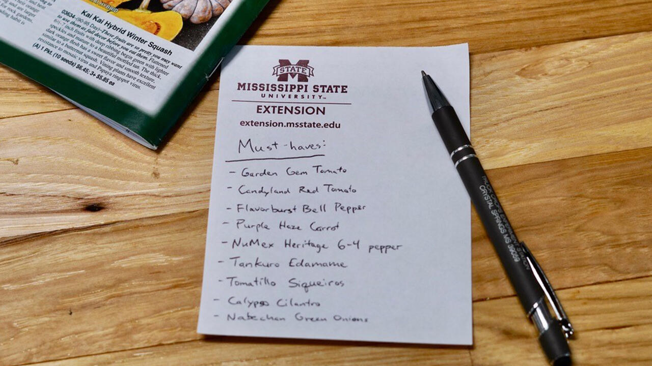 A handwritten list of plants lies on a wooden table.