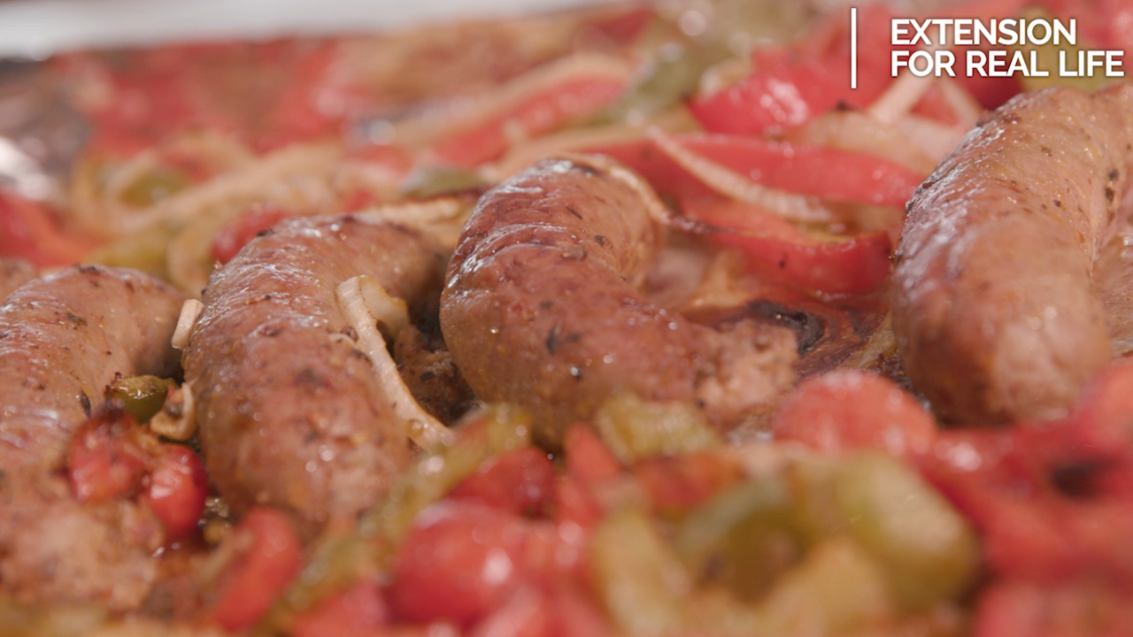 A pan of prepared Italian sausages with onions and green and red peppers.