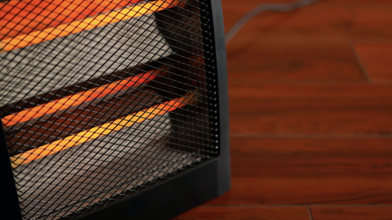 Close up of a space heater sitting on a hardwood floor