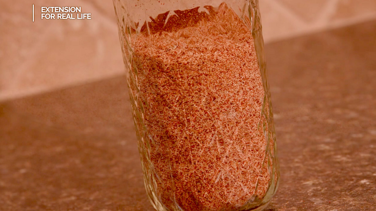 A pint glass jar filled with homemade taco seasoning sits on a kitchen countertop.