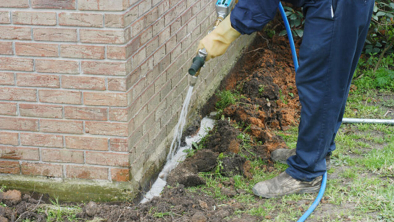 A pesticide technichian applies a termite treatment around a home foundation.