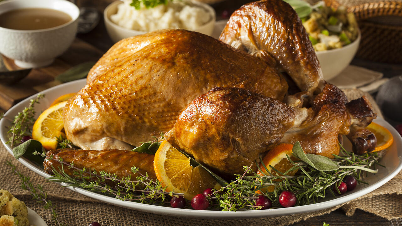 roasted turkey on a platter with herbs, cranberries, and orange slices