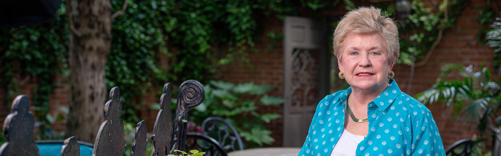 A person standing in a garden beside a plant. 