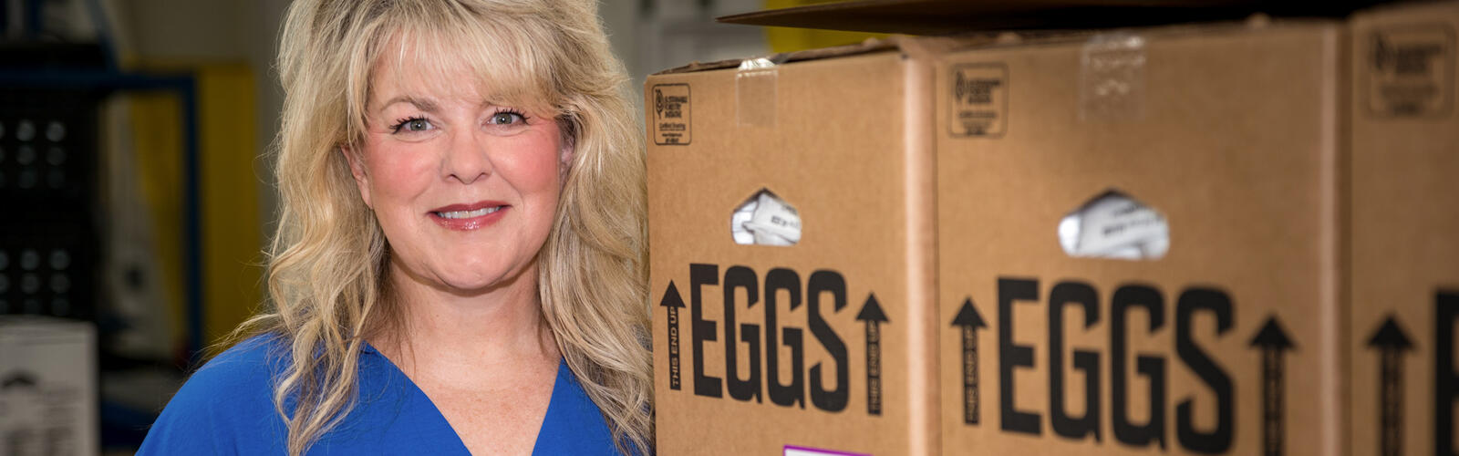 A person standing beside boxes of eggs.