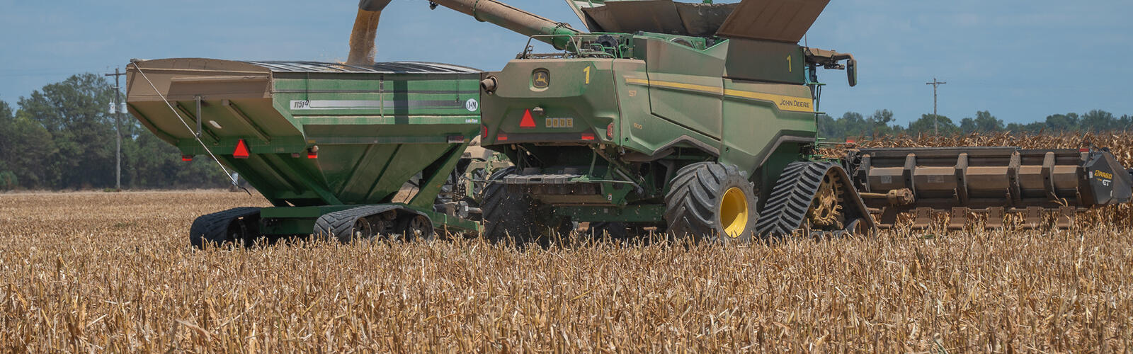 Corn is transferred in a field from the harvester to a grain cart.
