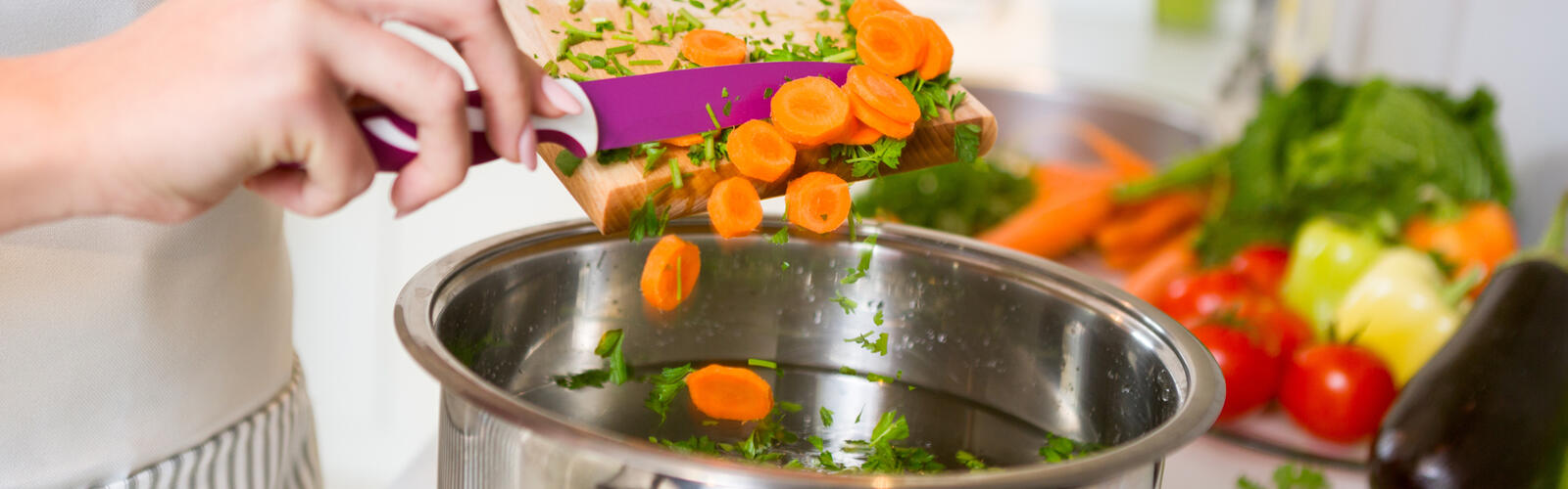 Person dumping vegetables in a pot.
