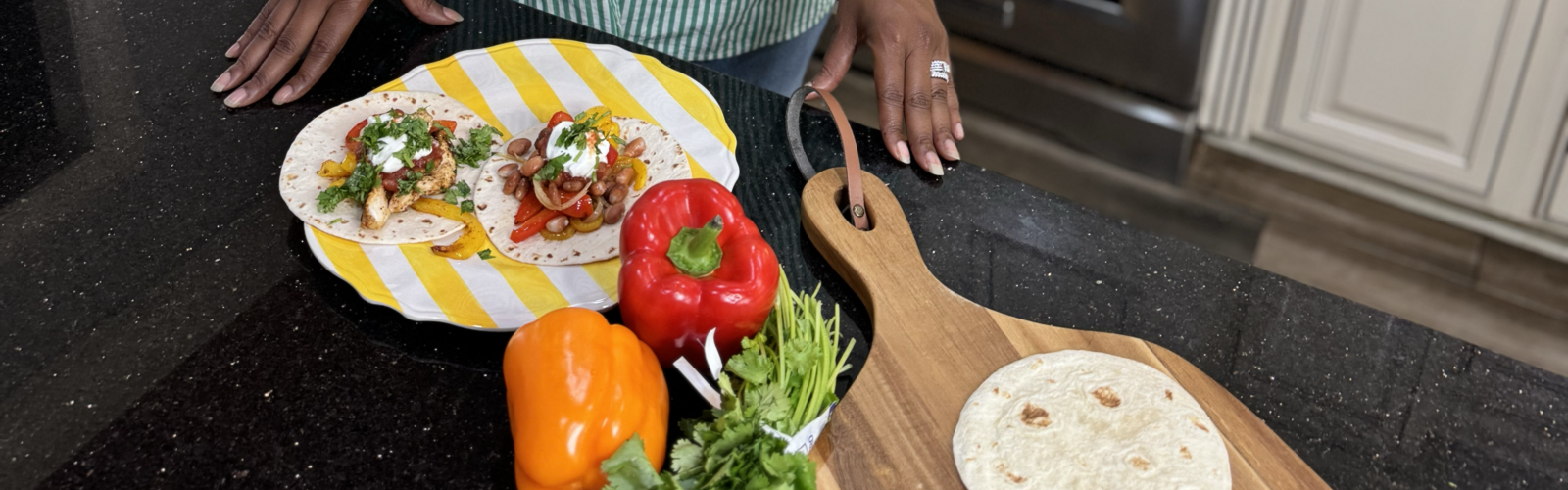 A woman in a kitchen with ingredients for fajitas on the counter.