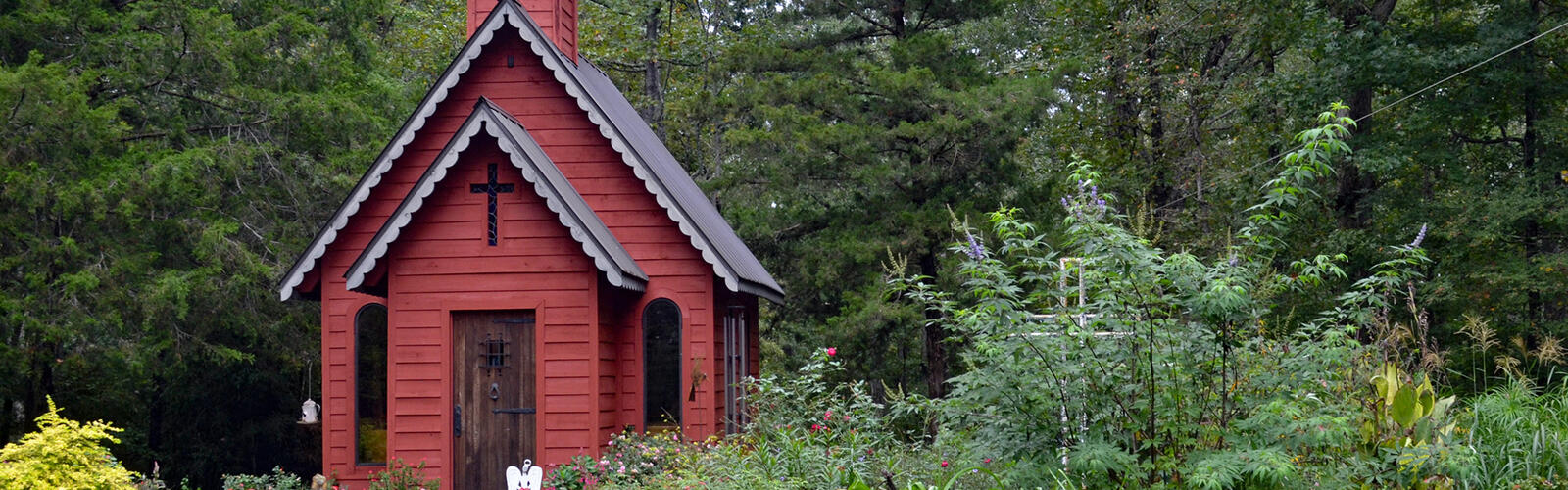 A small red structure stands in the center of a garden landscape.