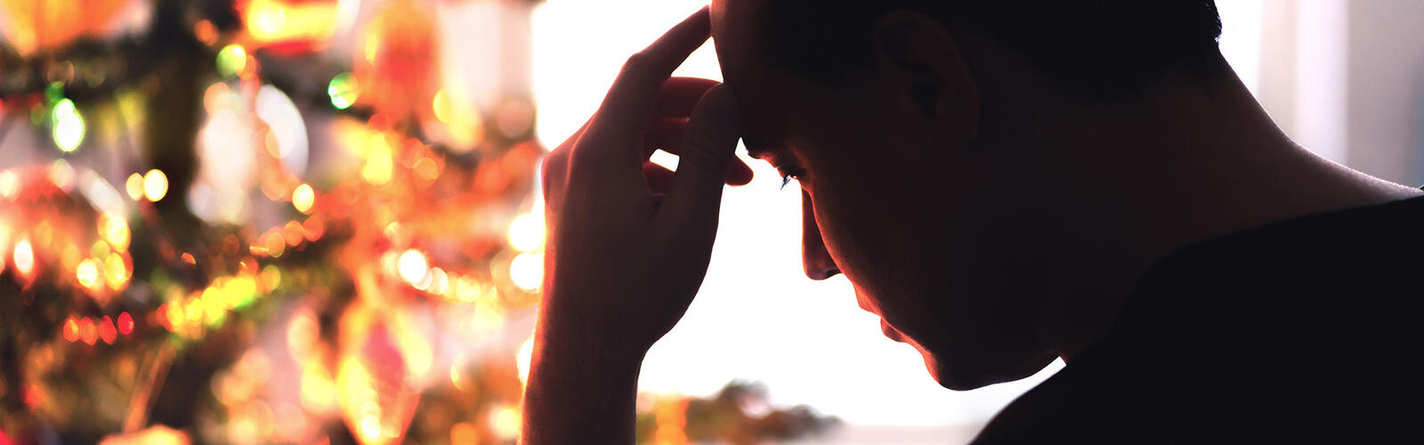 Man stressed out looking at a Christmas tree.