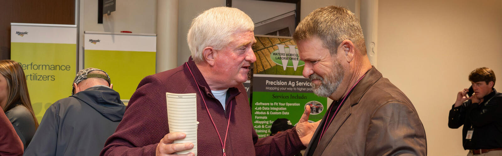 Two people speaking in front of an agricultural display.