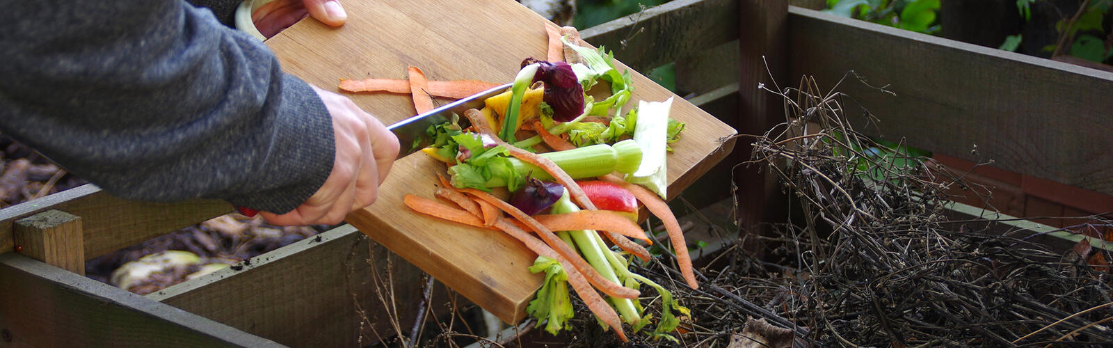 Person scraping compost vegetables in a compost pile.