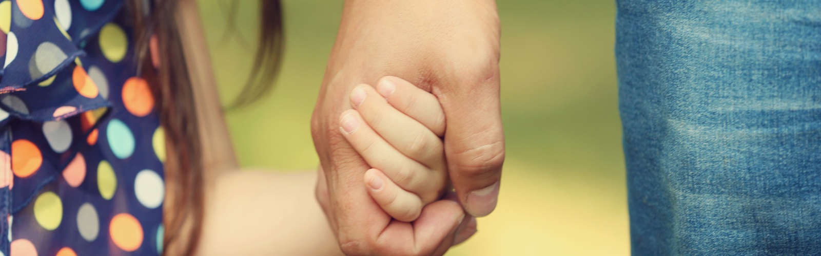 Close up picture of an adult holding a child's hand.