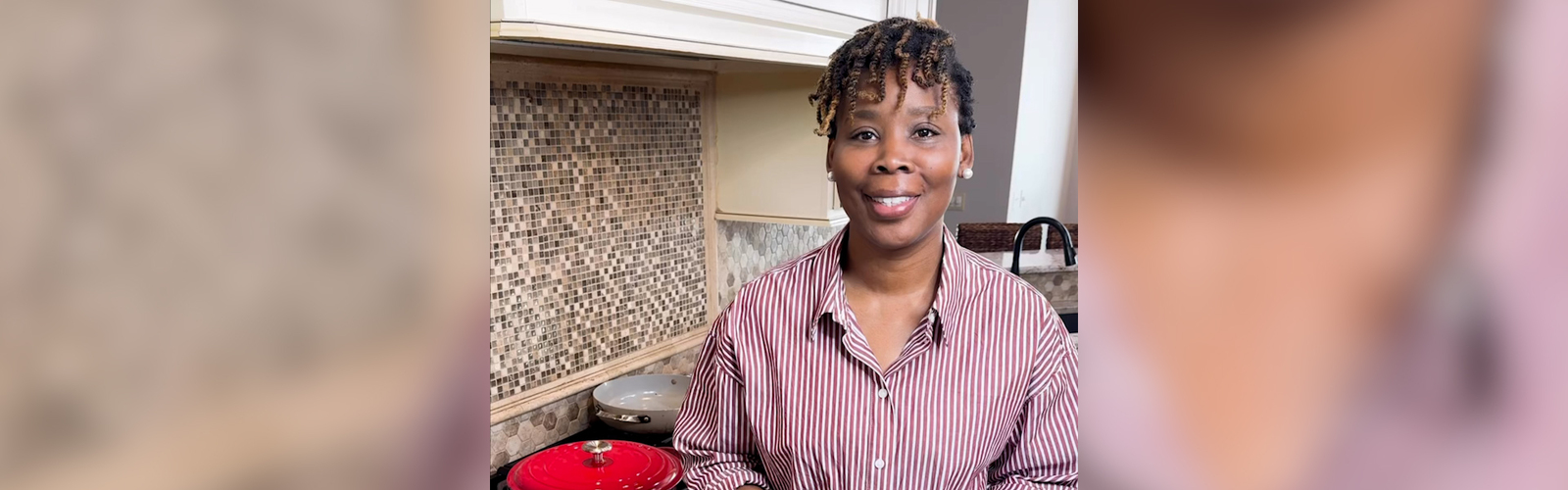 A person stands in a kitchen in front of the stove.
