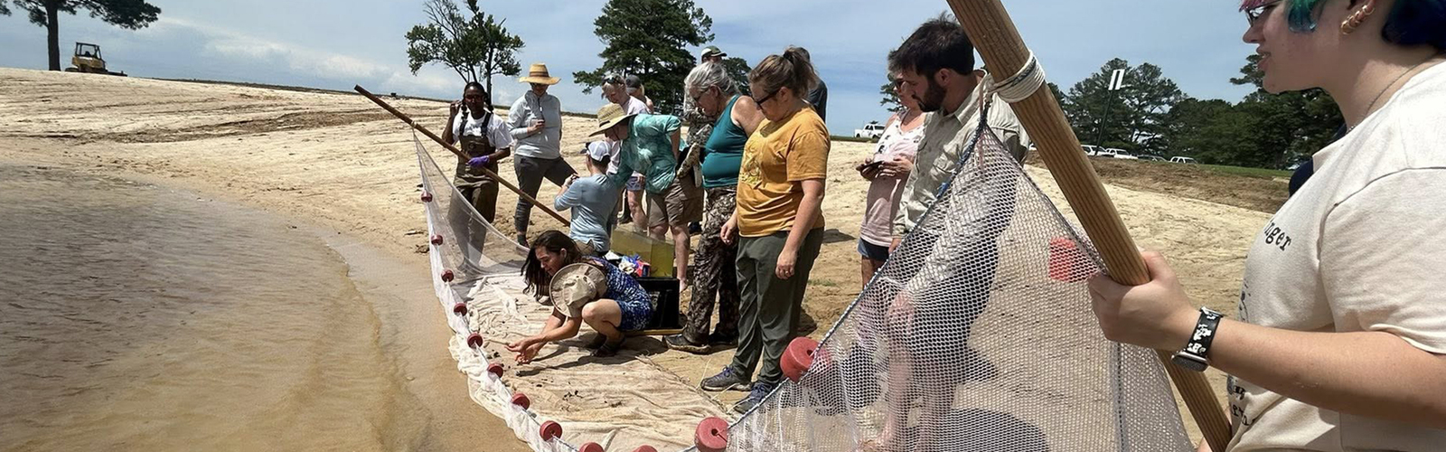 A group of people casting a new on the shore of the ocean.