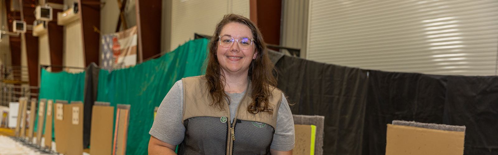 A person standing in an indoor shooting range and holding a firearm.