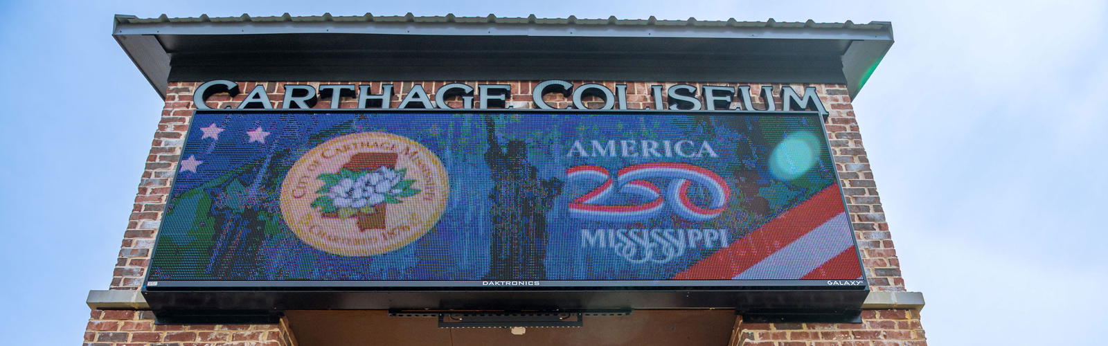 A sign on bricks that lists “Carthage Coliseum,” and “America 250 Mississippi” and shows the City of Carthage seal with a magnolia bloom in the center.