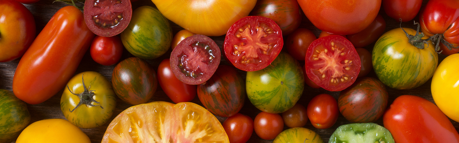 Close-up of colorful tomatoes, some sliced, shot from above