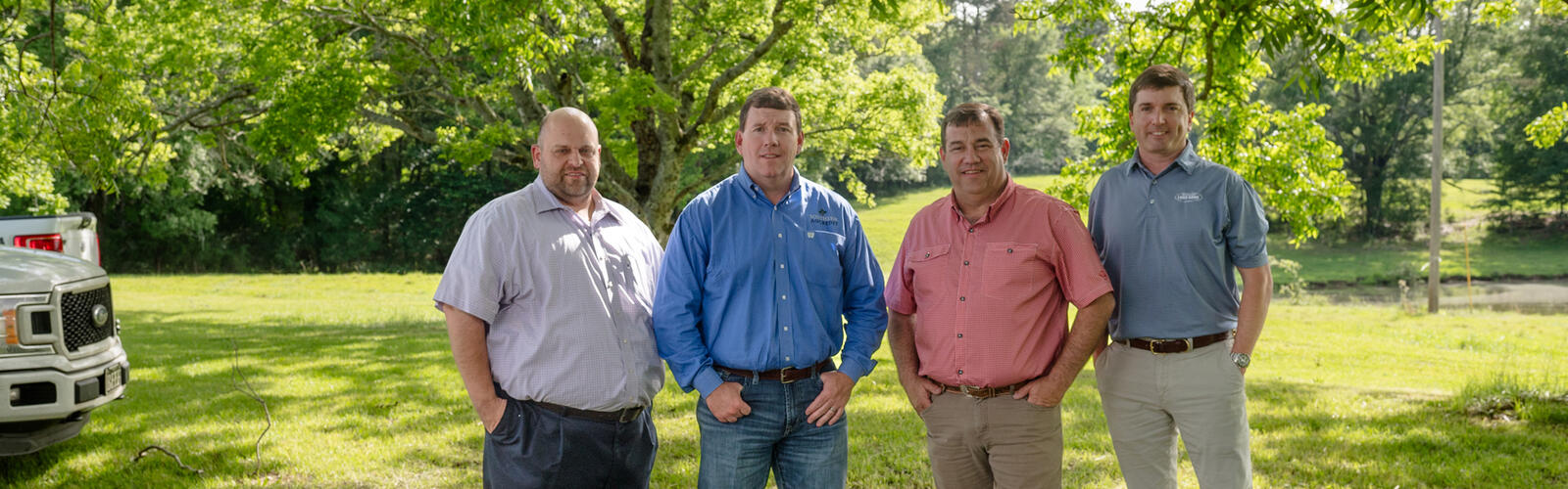 Four people standing outside, hands in their pockets.