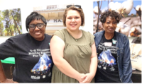 Three women standing in a row smiling for the camera