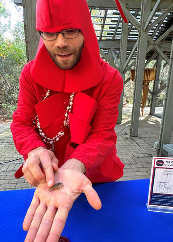A man dressed in a red crayfish suit holds a crayfish.