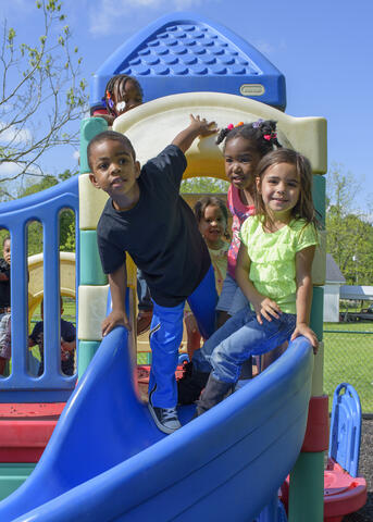 Children play on a multi-colored slide on a playground.