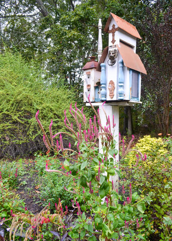 A birdhouse stands in a garden.