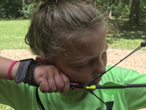 Young archer at full draw with bowstring touching the tip of the nose and resting at the corner of the mouth, demonstrating a consistent anchor point on the face.