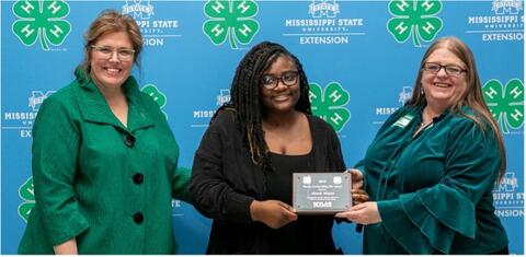 Two women present a woman with an award