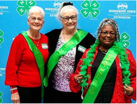 Three women show off their green 4-H sashes