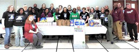 A group of people stand behind a table with care packages