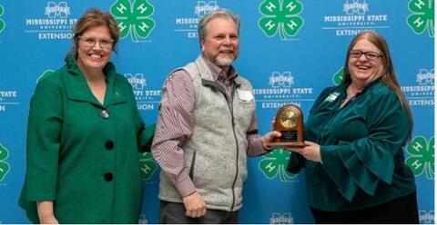 Two women present a man with the Kenneth Cook Award