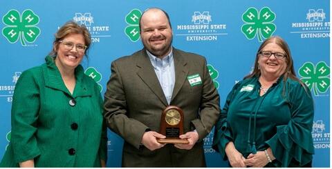 Two women present a man with the Kenneth Cook Award