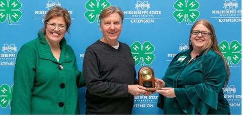Two women present a man with the Kenneth Cook Award