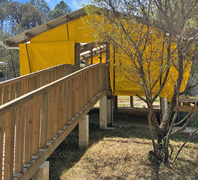 A raised wooden barn with yellow tarps covering its sides.