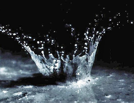 Close-up capture of an individual raindrop's impact when it hits bare soil.