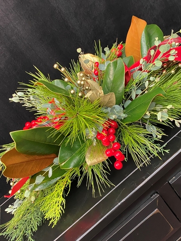 Table centerpiece of evergreens and red berries.
