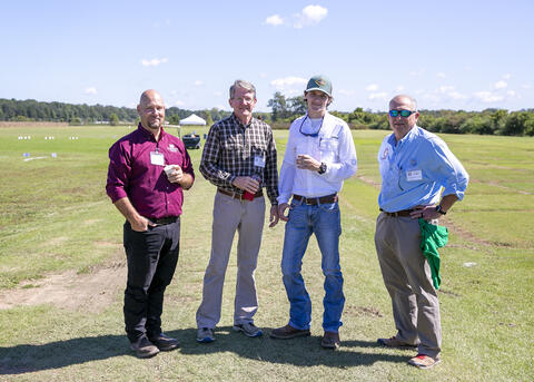 Four men stand in a sod farm.