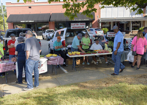 Shoppers browse products set up outdoors on tables.