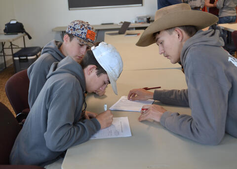 Young people work on a written task in a classroom.