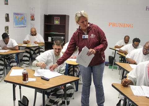 A woman hands out papers in a classroom.