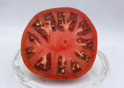 A sliced tomato sits in a glass dish.