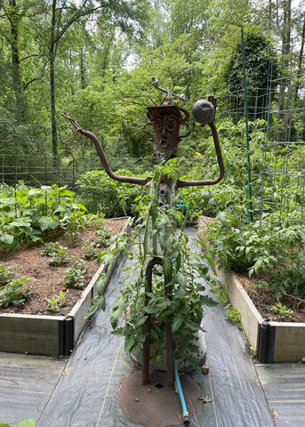 A metal statue has a plant growing around it.