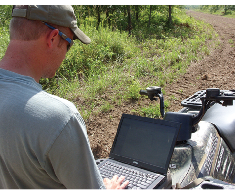 A person on an ATV uses a laptop.