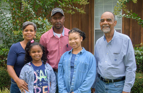 • A woman, man, and older man stand with two teen girls.