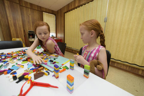 Two young girls with red hair working with Legos.