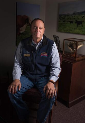A man sits in a chair with his hands on his knees.