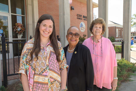 Three people stand in front of the city hall in Forest, MS.