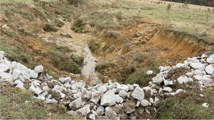 Figure 5B after: A deep trench with a wide strip of rocks crossing it.