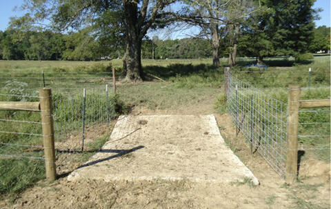 A concrete walkway and fencing in a field.
