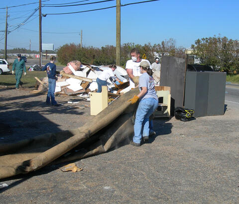 Several people pile debris next to a road.
